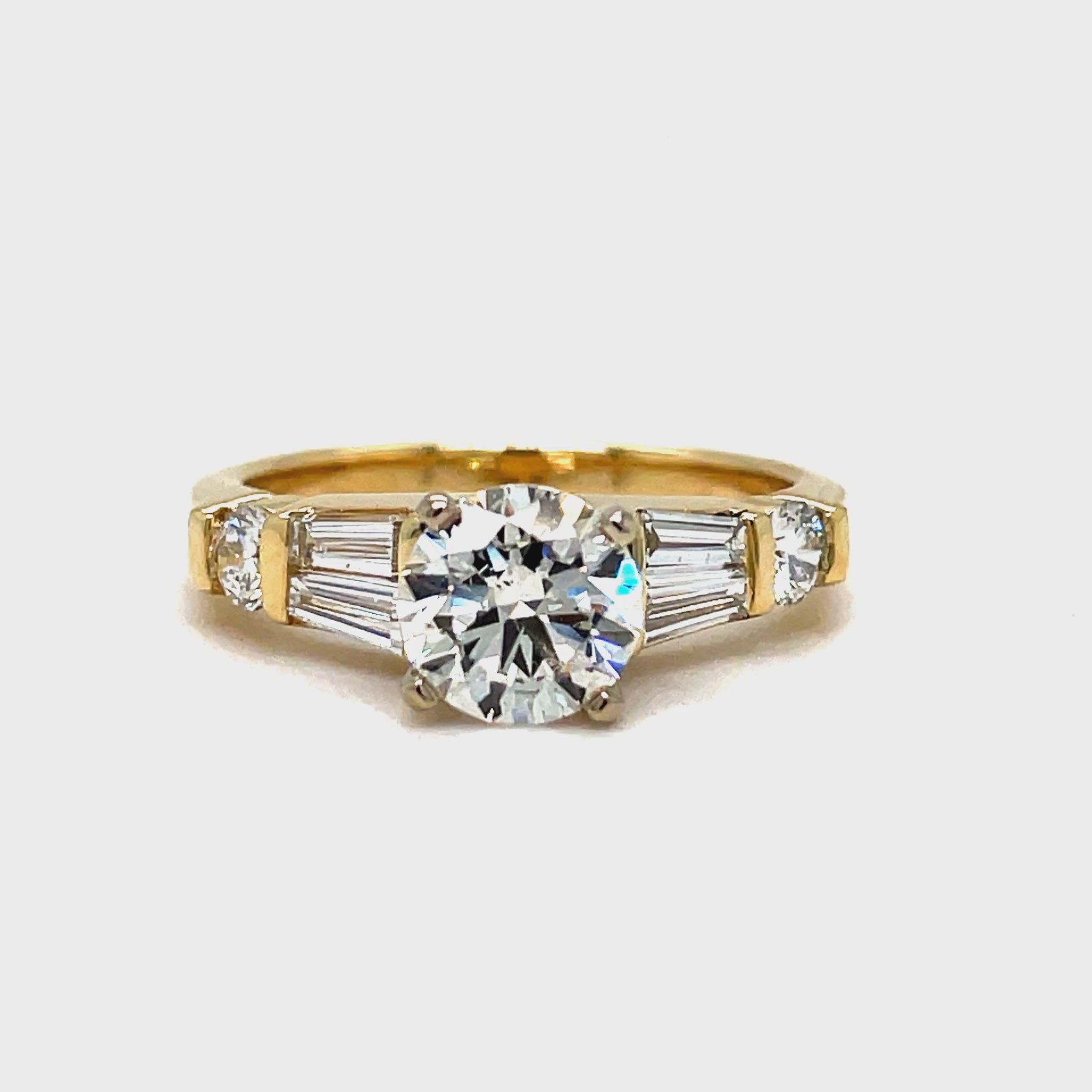 ndulge in luxury with this Round Brilliant Diamond & Baguette Engagement Ring. With a striking 1.02 ct round brilliant diamond, framed by tapered baguette diamonds and two small round diamonds totaling 0.40 cts, this exquisite ring exudes elegance and sophistication. Crafted in 14k yellow gold, it's the perfect symbol of your love.